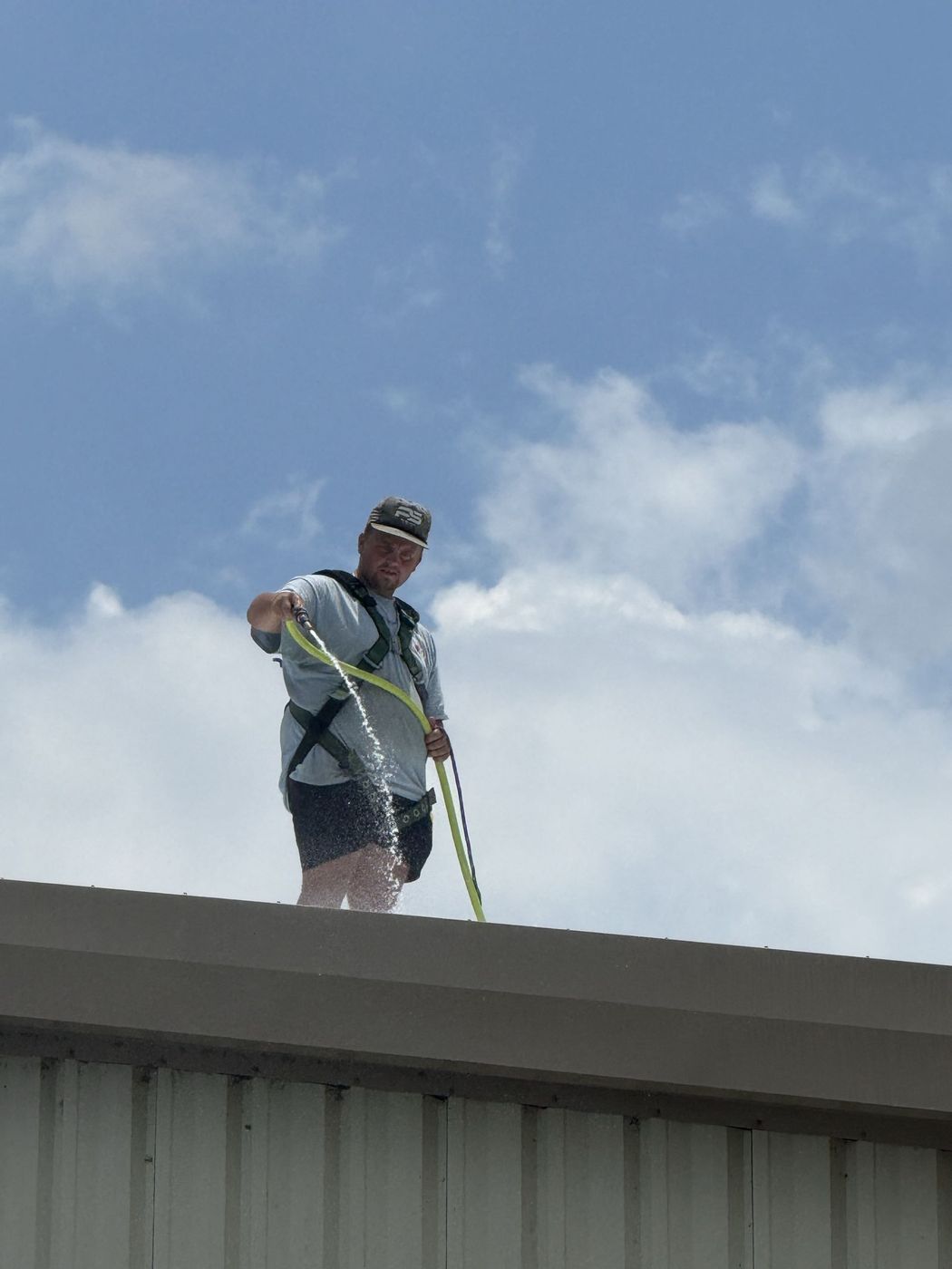 Working along a roof edge with a rinse hose